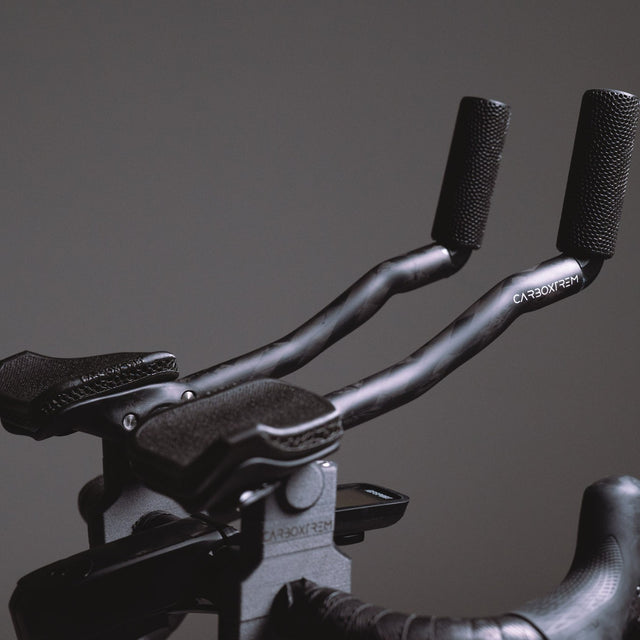 Acoples de triatlón CarboXtrem Aero montados en un manillar de carretera, con extensores de carbono y almohadillas de malla 3D