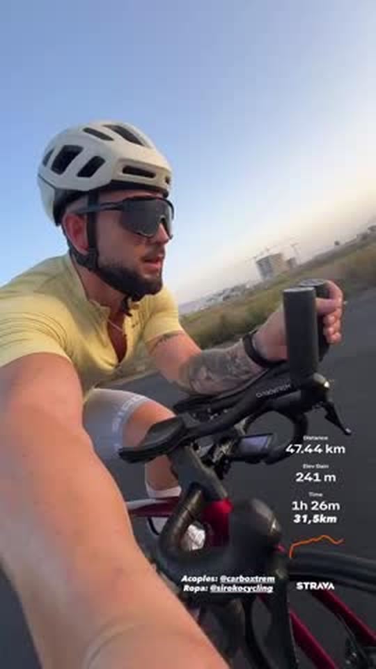 Ciclista sobre los acoples con los datos de la salida de Strava sobreimpresos